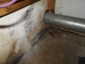 Why is it dangerous to run an exhaust duct for a gas clothes dryer through an air conditioning return air plenum?