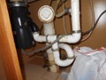 Why is garbage disposal not allowed at a combination waste and vent (CW&V) under a sink?