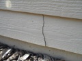 What causes vertical cracks in fiber cement siding planks?