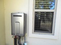 What is the minimum clearance to doors and windows for an outdoor tankless gas water heater?