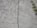 What causes a vertical crack in an exterior concrete block or brick wall?